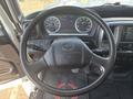 Steering wheel of a 2012 Hino 338 with dashboard gauges and controls visible in the background