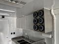 Interior view of a 2020 Freightliner MT45 featuring stainless steel cabinets and a kitchen sink with a paper towel holder mounted above