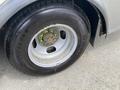 A close-up view of a tire on a 2020 Chevrolet Express showing visible wear and rust on the wheel rim and green lug nut accents