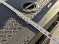 A close-up of the bed of a 2011 International 7500 showing a measuring tape laid across a textured surface with circular access points