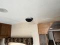 Ceiling speaker of a 2013 Outdoor Wind River camper with a black face and silver trim