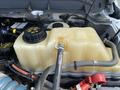 A 2015 Ford F-550 engine coolant reservoir with a black cap and connected hoses visible