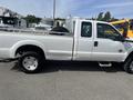 A 2014 Ford F-250 SD pickup truck in white color with a flatbed and a single cab design parked in a lot
