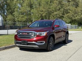 A red 2018 GMC Acadia parked with a sleek design featuring a prominent grille and stylish headlights
