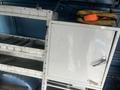 A 2009 Ford Econoline with metal shelving units and a closed white cabinet in the interior scene