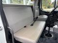 Interior of a 2013 Freightliner 114SD showing a gray two-person bench seat and a gear shifter on the floor