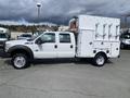 A white 2015 Ford F-550 with a double cab and utility box on the back equipped with storage compartments and equipment holders