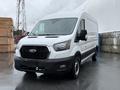 A 2022 Ford Transit van in white with a black grille and headlights parked on a wet surface