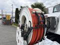 A 2016 Peterbilt 348 with a large hose reel mounted on the back featuring bright orange hoses coiled around it