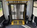 A 2018 Ford Transit-350 interior featuring a foldable wheelchair lift with a black mesh enclosure and yellow safety features