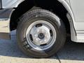 A close-up of a silver wheel from a 2019 Chevrolet Express featuring a round rim and a black tire with visible tread