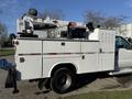A 2009 Ford F-550 utility truck with a white body features storage compartments and a mounted crane on the rear for lifting tasks