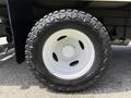 A close-up of a white wheel with a rugged tire tread designed for off-road use mounted on a 2018 Ford E-450