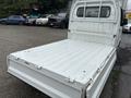 A 2010 Suzuki Carry with a flatbed design showcasing a clean, white metal cargo area and an open rear configuration