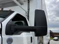 A 2019 Ford F-750 truck with a large side mirror reflecting its surroundings and a certification sticker on the door