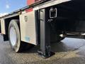 A 2010 International 4300 truck with a flatbed and diamond plate side panel featuring a black trailer hitch and secured chains