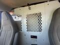 A 2017 Chevrolet Express interior view featuring two front seats and a partition with a diamond mesh design and control panel visible beneath