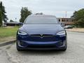 A blue 2020 Tesla Model X facing forward with a sleek design and the iconic Tesla logo on the front grille