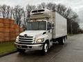 A white 2017 Hino 338 box truck with a Thermo King refrigeration unit on top and a shiny front grille parked on a street