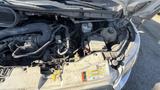 A 2021 Ford Transit with the hood open revealing the engine compartment and various components including hoses battery and reservoir