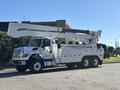 A white 2013 International 7500 truck with an elevated bucket and extended boom for utility work