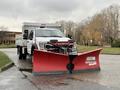 A 2021 Ford F600 with a large red snow plow attached to the front and a truck bed for transporting materials
