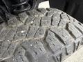 Close-up of a rugged tire tread from a 2017 Chevrolet Silverado 1500 with deep grooves and dirt particles embedded in the rubber