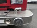 A close-up of a 2006 E-One fire truck's front bumper featuring a shiny silver hose connection and a circular speaker or grille on the side