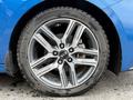 Close-up of a silver alloy wheel with a black center cap featuring the brand name and a high-performance tire with visible tread pattern
