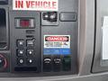 Dashboard controls of a 2020 Peterbilt 330 featuring a warning label a series of buttons for various operations and a gear selector