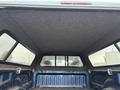 Interior view of a blue 2006 Dodge Ram 2500 truck bed showing a carpeted canopy with side windows and no visible cargo or tools inside