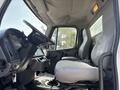 Interior of a 2014 Freightliner M2 106 featuring two gray seats and a large steering wheel with a dashboard visible on the left side