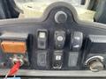 The control panel of a 2012 John Deere 310SJ featuring various switches and a key ignition with labels for different functions