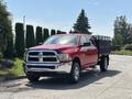 A red 2013 RAM 2500 pickup truck with a chrome grille and a black flatbed attached standing on a paved surface