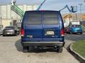 A blue 2013 Ford E-350 Super Duty van viewed from the rear with a partial view of the license plate and large tires