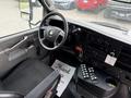 Interior view of a 2020 Chevrolet Express showing the driver's seat steering wheel and dashboard with controls and a thank you mat on the floor