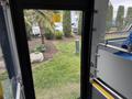Interior view of a 2018 Grande West Vicinity bus showing a door opening towards a green area with plants and a rock