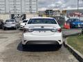 A white 2014 Hyundai Sonata hybrid viewed from the rear with no license plate visible