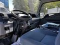 Interior view of a 2013 Mitsubishi Fuso FE160 featuring a steering wheel dashboard and driver's seat with blue upholstery