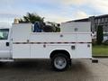 A 2010 Ford F-550 truck with an enclosed service body featuring storage compartments and a mounted reel on the side