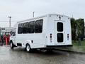 A white 2015 Ford Econoline shuttle bus with large windows and a rear door parked on a wet surface