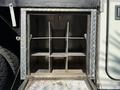 A metal storage compartment with six divisions appears empty and has a diamond plate texture on the door and floor