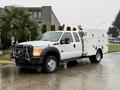 A white 2015 Ford F-450 utility truck with a fitted service body and safety lights on the roof