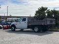 A 2013 RAM 5500 truck with a flatbed and dual rear wheels parked on a gravel surface