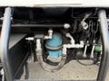 Close-up of a 2010 Autocar Xpeditor's engine compartment featuring various hoses and a blue fuel filter connected with metal fittings and a protective covering
