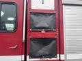A red 2006 E-One Typhoon fire truck featuring two black storage compartments mounted on its side with metal fittings