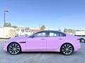 A pink 2020 Jaguar XE sedan with sleek lines and sporty wheels is parked in a lot showcasing its modern design and luxury features