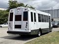 A 2020 Chevrolet Express bus with a primarily white exterior and black lower panels featuring multiple rear lights and large windows on the side