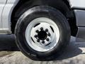Close-up of a white wheel and tire of a 2023 Ford E-450 featuring black lug nuts and a smooth, robust tire tread