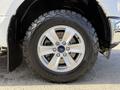 A 2018 Ford F-150 wheel with a five-spoke alloy rim and off-road tire showcasing the Ford logo on the center cap